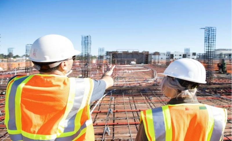 Female & male construction worker looking at construction site